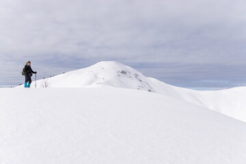 Senior woman is snowshoe hiking in alpine snow winter mountains. Allgau, Bavaria, Germany.