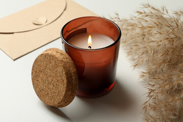 Scented candle, envelope and reed on white background