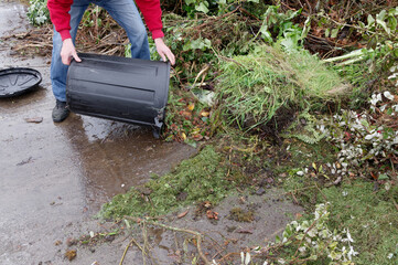 A person is emptying a black bin that has the weekly decomposable waste in it
