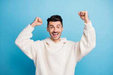 Fototapeta premium Photo portrait of man with bristle celebrating raising two fists isolated on pastel blue colored background