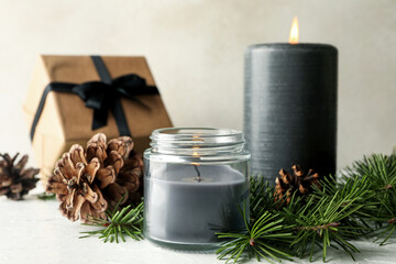 Scented candles, gift box and pine branches with cones on white table