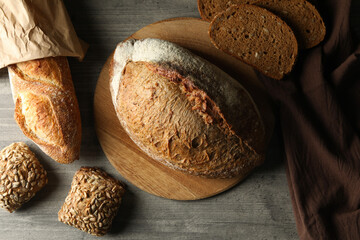 Board with fresh bread and napkin on gray table
