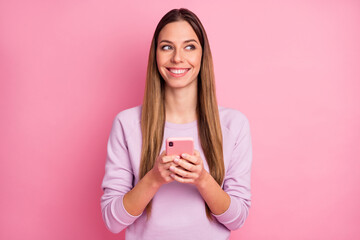 Close-up portrait of charming cheerful straight-haired girl using cell app web dating service isolated over pink color background
