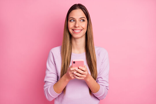 Close-up portrait of charming cheerful straight-haired girl using cell app web dating service isolated over pink color background