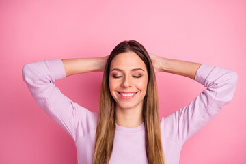Obraz na płótnie Canvas Close-up portrait of lovely dreamy straight-haired girl holding hands behind head relaxation isolated over pink color background
