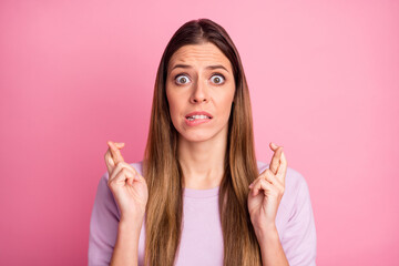 Close-up portrait of pretty confused straight-haired girl asking favor expecting crossed fingers isolated over pink color background