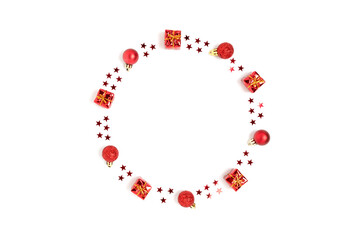 Wreath made of red Christmas toys and confetti. Monochrome festive frame on a white background.
