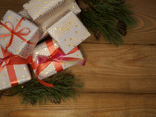 Christmas background with boxes of gifts with red ribbon, pine cones, pine branches on a wooden background with space for text