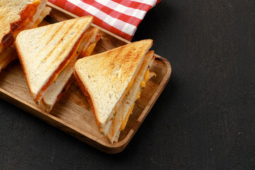 Sandwiches cut into halves on wooden cutting board with napkin