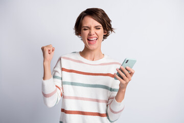 Fototapeta premium Photo of impressed lucky young woman dressed striped pullover holding modern device arm fist isolated grey color background