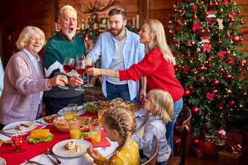 family having christmas dinner at home, drinking red wine and clinking glasses together, have fun celebrating