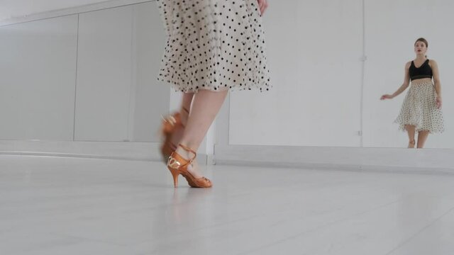 Young beautiful girl dancing ballroom dancing. A professional ballroom dancer is engaged in a large white hall.