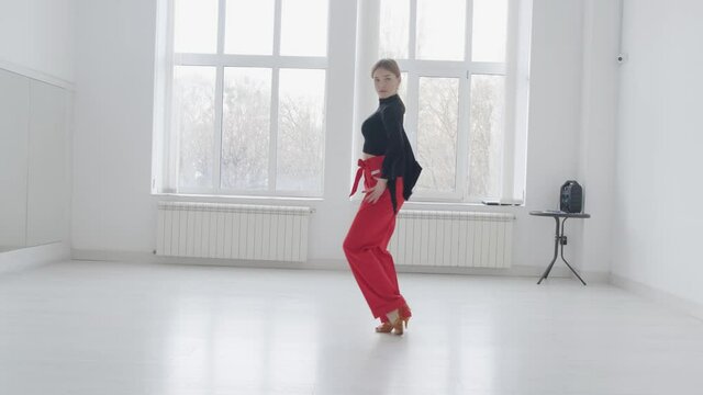 Young beautiful girl dancing ballroom dancing. A professional ballroom dancer is engaged in a large white hall.