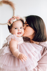 a young mother in a beautiful dress kisses her little daughter. the concept of a happy family