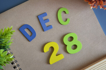 December 28, Cover design in natural concept with a brown notebook and colorful wooden alphabet.