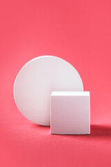 Abstract empty geometric shape podium for product on pastel red background. Copy space. White cube on pink backdrop. Pedestal template for advertising. Trendy minimal concept. Mock up
