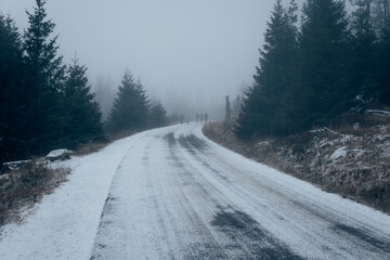 Fototapeta premium Verschneite Brockenstraße mit Nebel und Wanderer