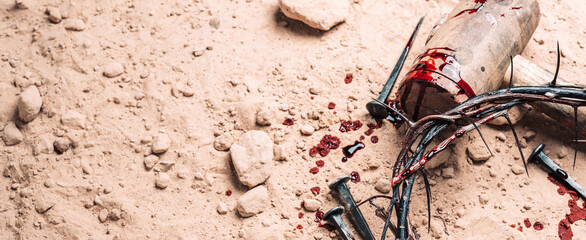 Old wooden cross, hammer, bloody nails and crown of thorns on ground. Banner. Copy space. Good...