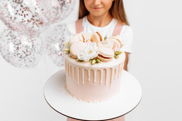 little girl holding a beautiful big birthday cake, birthday celebration with balloons, over white background