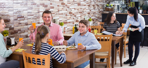 Young family with teenagers having lunch in cozy cafe