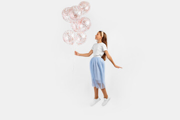 funny young girl jumping high celebrating and holding colorful balloons isolated on white background. Birthday party