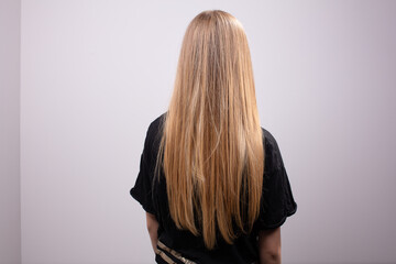 Back of girl with beautiful long blonde hair wearing black sweater - obrazy, fototapety, plakaty