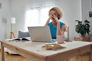 Obraz premium Woman working from home and being depressed, tired with headache. Modern concept and problems with freelancers.