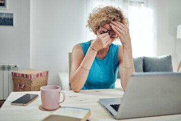 Woman working from home and being depressed, tired with headache. Modern concept and problems with...