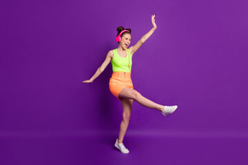 Full length body size view of pretty fit overjoyed cheerful girl jumping listening hit dancing isolated on bright violet color background