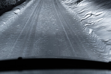 Car tracks on winter road covered with snow, driver perspective