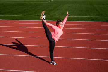 Stretching away the stress. child training at school physical education lesson. girl stretching before training. gymnast prepare for competition. athlete warming up on stadium gym. flexibility