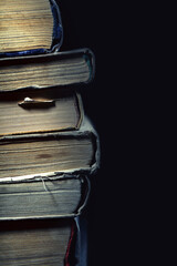 Stack of old dusty shabby books on black background