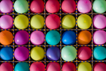 Inflated balloons of different colors in square rope cells. Bright, fun abstract background illuminated by the sun