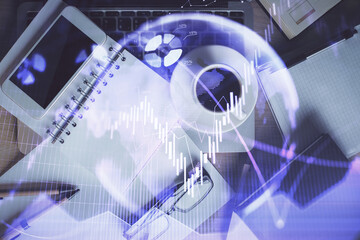 Double exposure of financial graph hologram over desktop with phone. Top view. Mobile trade platform concept.