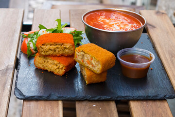 Classic, Italian arancini. deep fried Rice balls with minced meat and some vegetables inside. Tasty crunchy food with peanuts sauce and tomatoes soup with mozzarella cheese on the top. Close up view