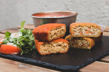 Classic, Italian arancini. deep fried Rice balls with minced meat and some vegetables inside. Tasty crunchy food with peanuts sauce and tomatoes soup with mozzarella cheese on the top. Close up view