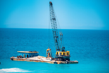 Fototapeta premium The ship is mining stone and sand in the sea