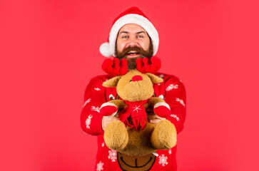 Happy man playful mood. Hipster man hold Christmas gift. Merry xmas. Happy new year. Oh my deer. Helping Santa Claus. Symbol of Christmas. Christmas eve. Dear Santa. Bearded man reindeer toy