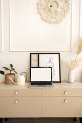 Laptop computer with blank screen on table with boho decorations. Minimal boho styled interior design template with mockup copy space.