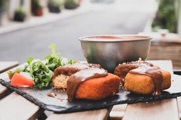 Classic, Italian arancini. deep fried Rice balls with minced meat and some vegetables inside. Tasty crunchy food with peanuts sauce and tomatoes soup with mozzarella cheese on the top. Close up view