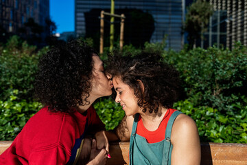 Fototapeta premium Smiling lesbian couple embracing and relaxing on a park bench