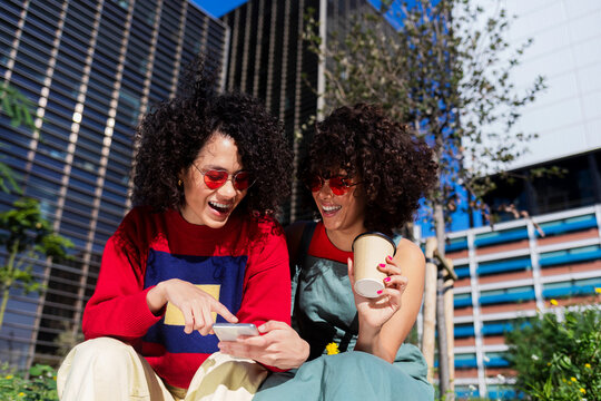 Beautiful women using a mobile in the street while sitting on a bench outdoors