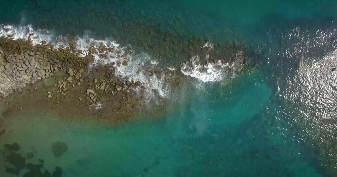 Bird eye view of a rock breakwater and waves hitting against it