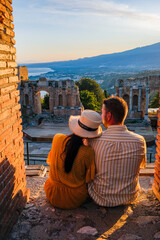 Taormina Sicily, couple watching sunset at the Ruins of the Ancient Greek Theater in Taormina,...
