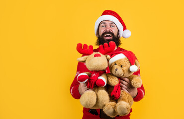 brutal bearded guy in santa claus hat and sweater with toys on christmas eve, christmas toys