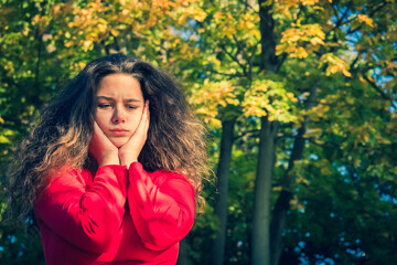 Portrait of angry teenager looking down while standing alone outside in the park. Copy space