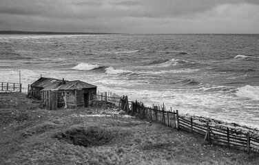 Dramatic black and white seascape with a raging White sea and a fishing hut on the shore. Kandalaksha bay. Umba. Russia