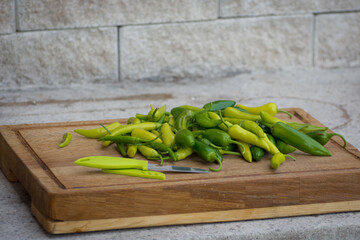 Cutting fresh home grown chillies on wooden board.