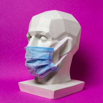 Plaster head in a medical bandage on a pink background. Gypsum head.