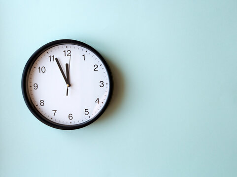 Round wall clock on blue surface showing 12 oclock, layout, top view, place for text.